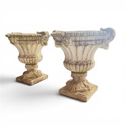 Pair of Neoclassical design cast stone garden urns, each of campana form with fluted body and gadrooned underbelly, decorated with faun/satyr opposing masks and ropetwist handles, with floral and mask design to the socles, raised on square bases, finished in weathered white patina