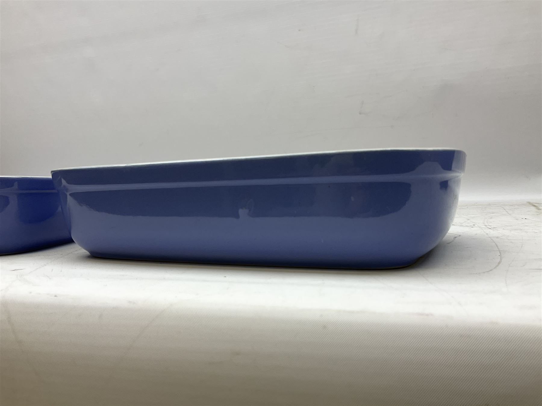 Emile Henry covered casserole dish of oval form in two tone brown and cream, no. 03.06, together with cast iron Nomar twin handled lidded casserole dish of oval form in navy, and other ovenware including Flintware ICTC, largest L35cm