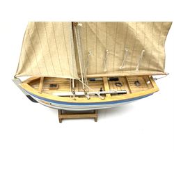Wooden model of RMS Titanic, on a fixed black stand bearing plaque inscribed 'Titanic 1912', L54cm, H22cm, together with model of a sloop, gaff rigged on stand bearing plaque inscribed 'Sloop' L32cm, H42cm; and model of a fishing trawler on a stand bearing plaque inscribed 'Chalutier' L35cm, H28cm (3)
