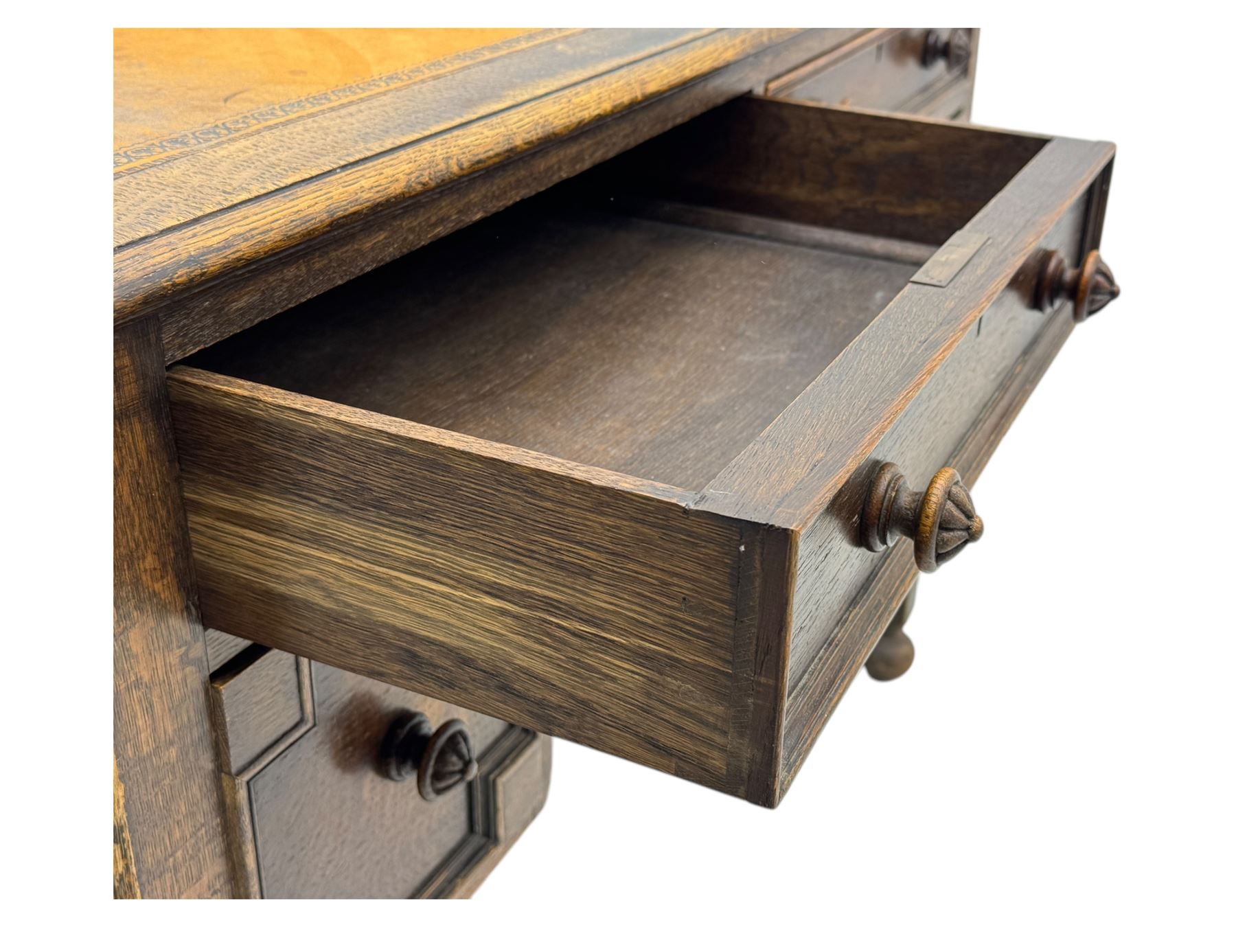 Early 20th century Jacobean design oak desk, with rectangular top inset with worn tooled leather, two frieze drawers over pedestals each fitted with a pair of panelled drawers, turned handles, on carved and fluted tapering legs united by stretchers 