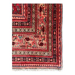 Persian Arak crimson ground rug, the field decorated with repeating Boteh motifs within geometric guard stripes