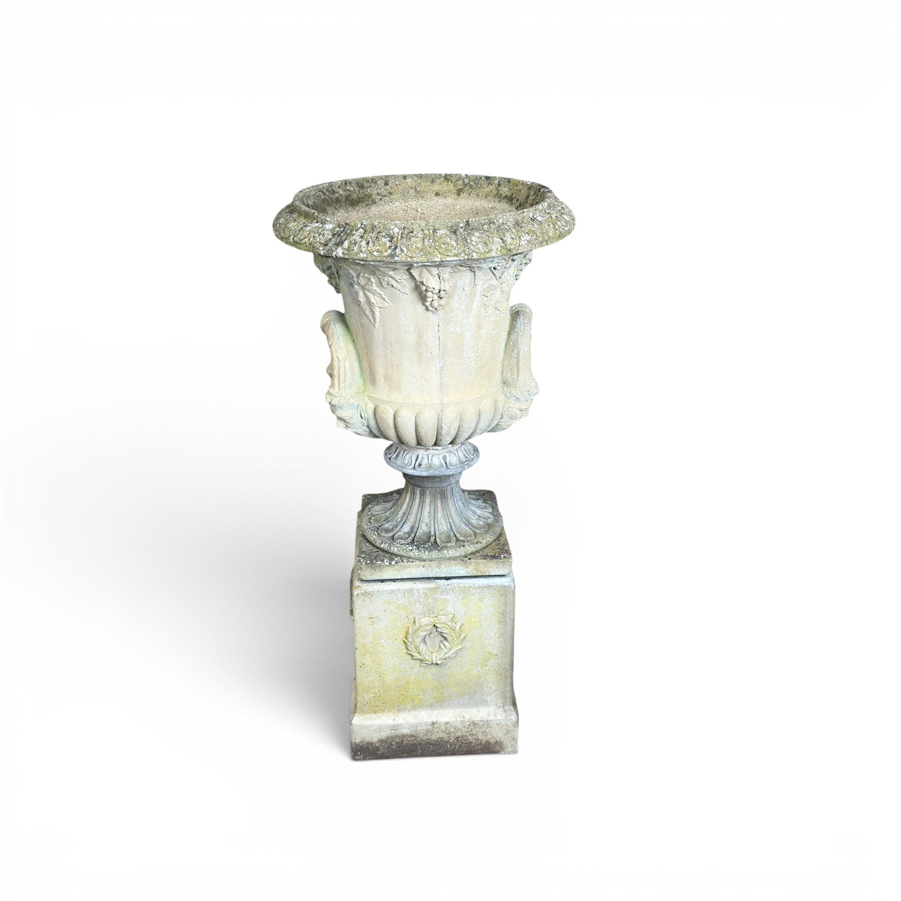 Cast stone classic garden urn, the rim decorated with leaves and berries, twin handles with face masks, raised on square base, stamped HGC