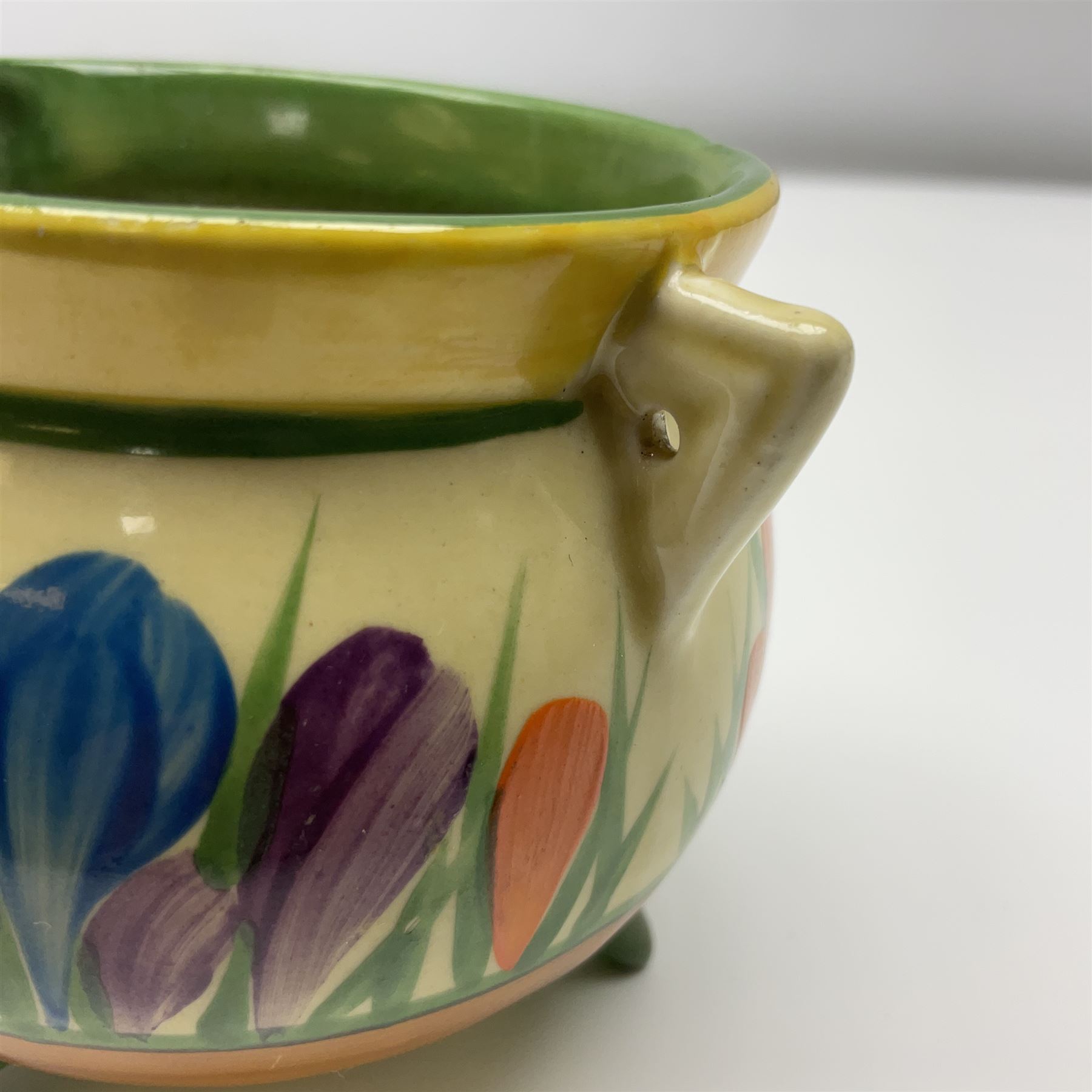 Clarice Cliff Bizarre for Newport Pottery, small bowl in the form of cauldron painted in the Crocus pattern, bordered by brown and yellow banding, with angular handles and raised upon three peg feet, with green printed mark and painted CROCUS beneath, circa 1929, H7cm