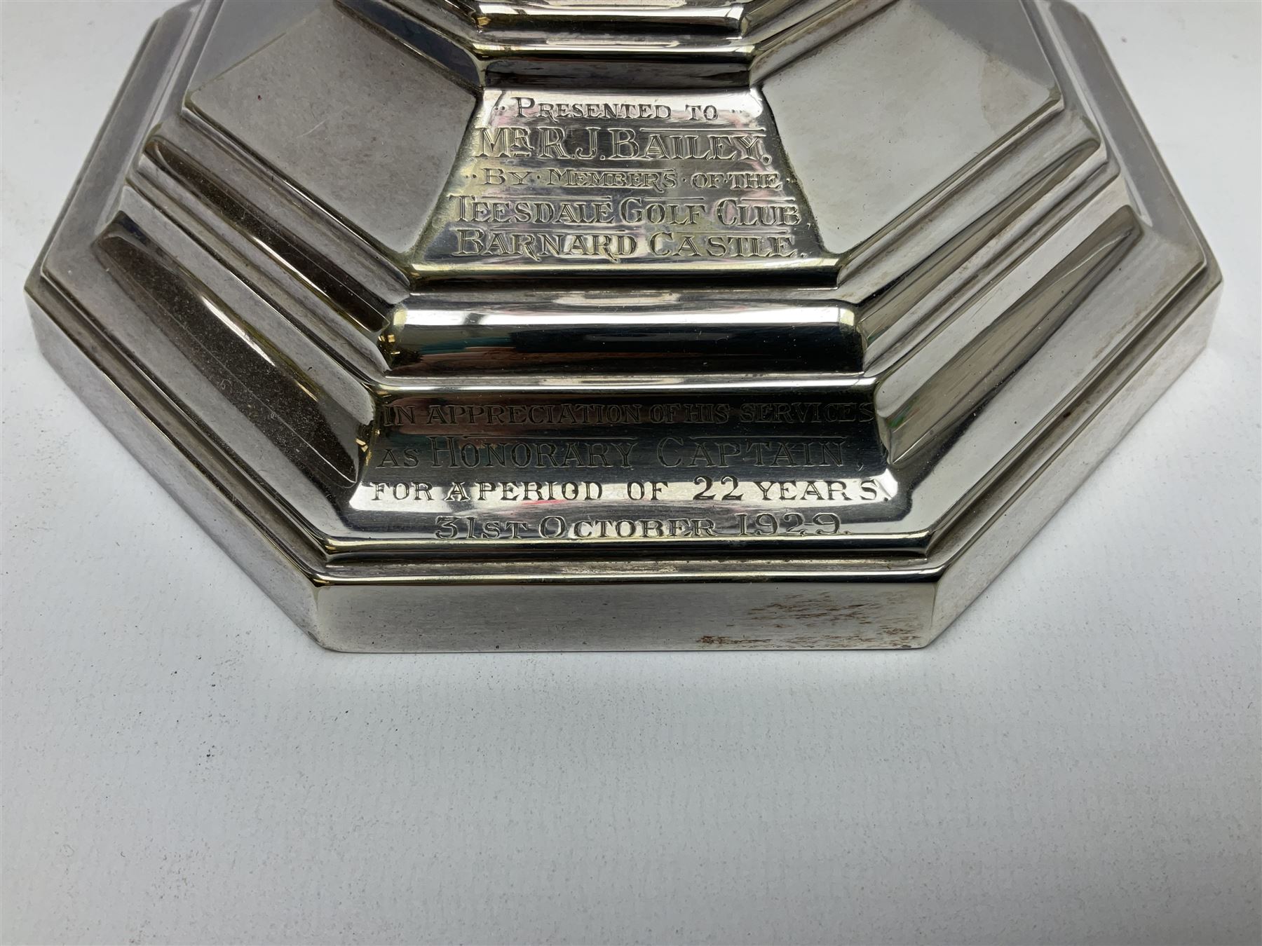 20th century Hawksworth, Eyre & Co silver plated oil lamp, the octagonal stepped base with engraved dedication, leading to an octagonal column supporting a faceted clear glass reservoir, Hinks Duplex burner, clear glass chimney, and cranberry glass shade, overall H71.5cm