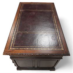 Victorian carved oak twin pedestal desk, moulded and foliate carved rectangular top with leather inset, fitted with nine drawers, each carved with scrolling foliage and lion mask handles, on skirted base 