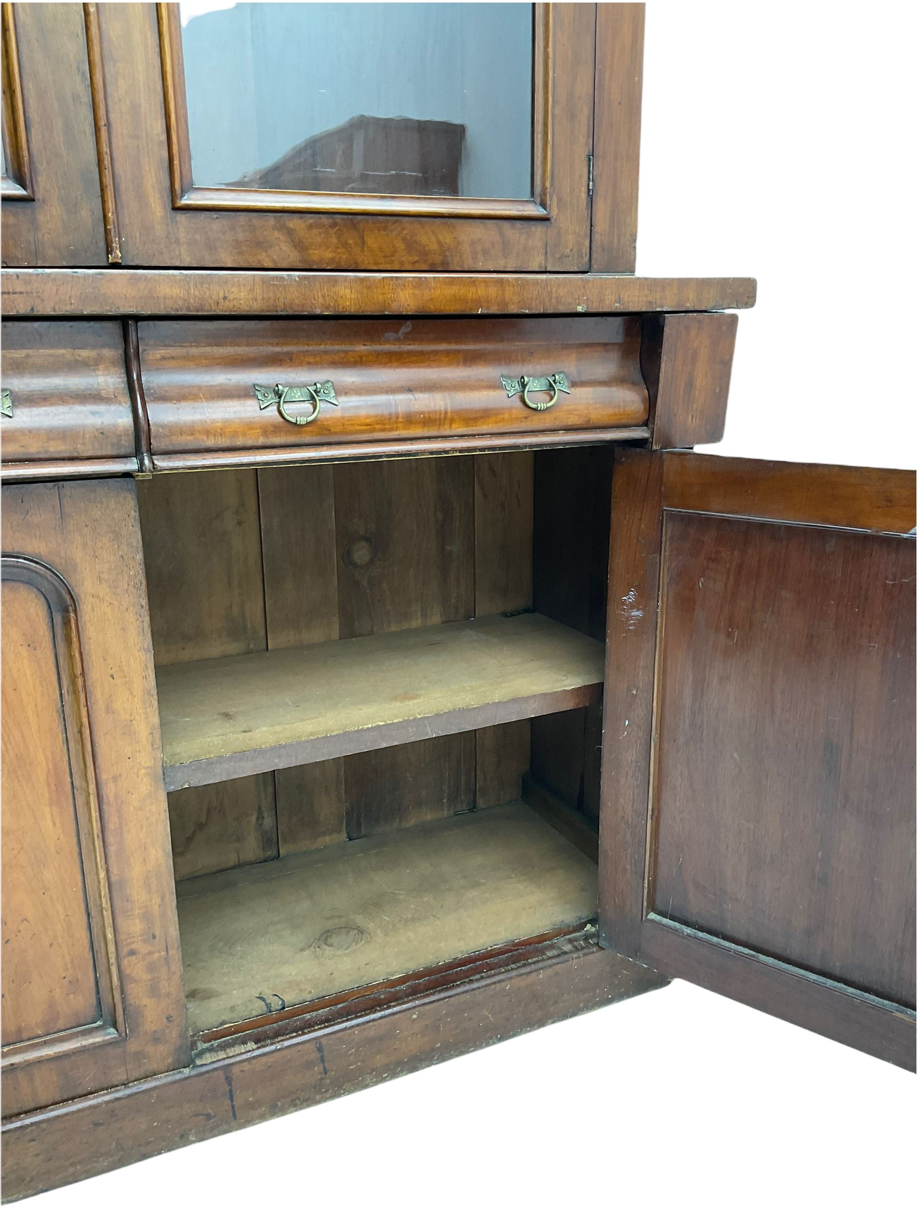 Victorian mahogany bookcase on cupboard, projecting cornice over two glazed doors and carved corbels, fitted with two drawers and double cupboard, plinth base
