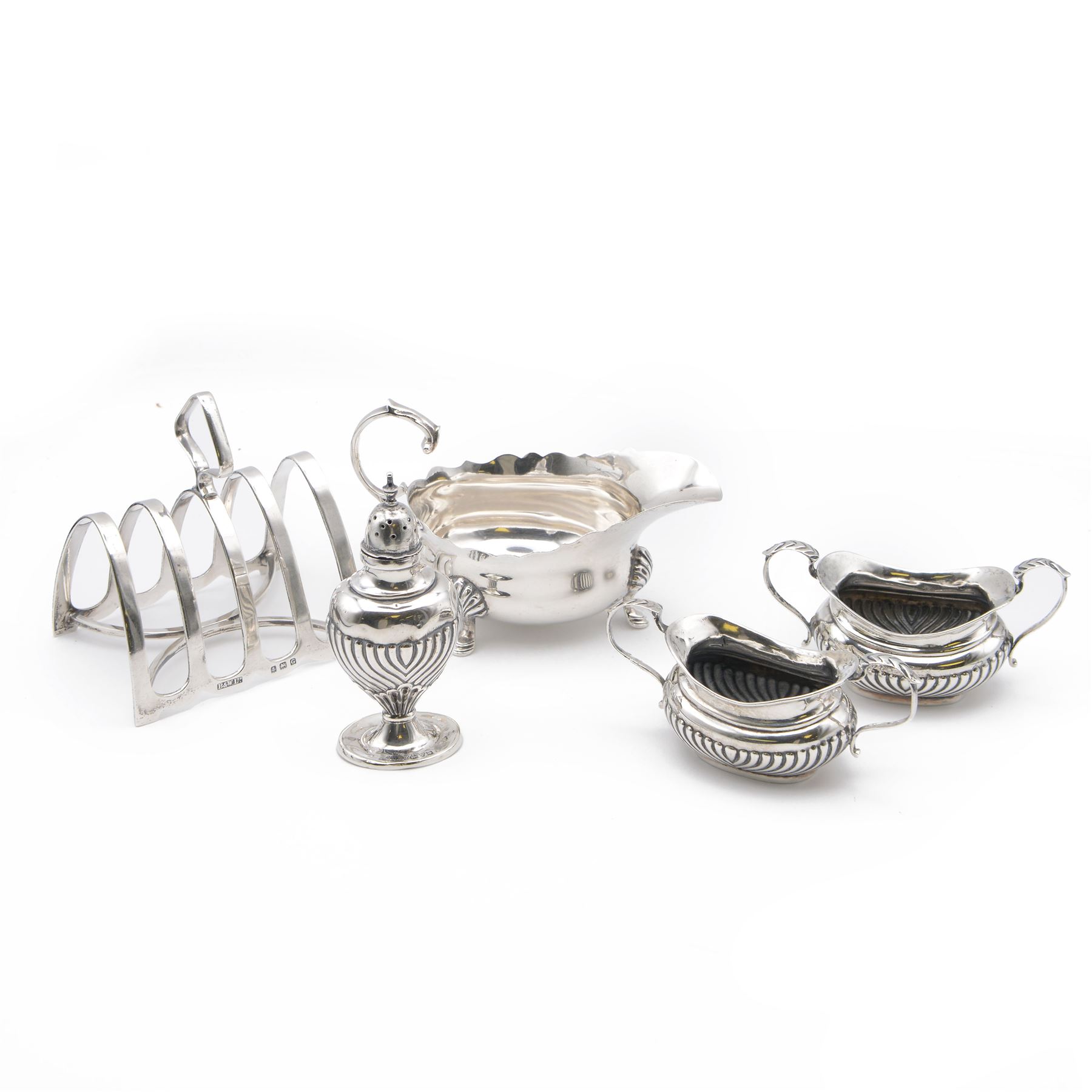 Group of silver, comprising 1930s five bar toast rack, hallmarked B & W Ltd, Birmingham 1931, three piece Edwardian silver cruet set comprising two open salts and a pepper shaker, hallmarked E J Trevitt & Sons, Chester 1904 and a small 1930s silver sauce boat, hallmarked Edward Barnard & Sons Ltd, London 1937 
