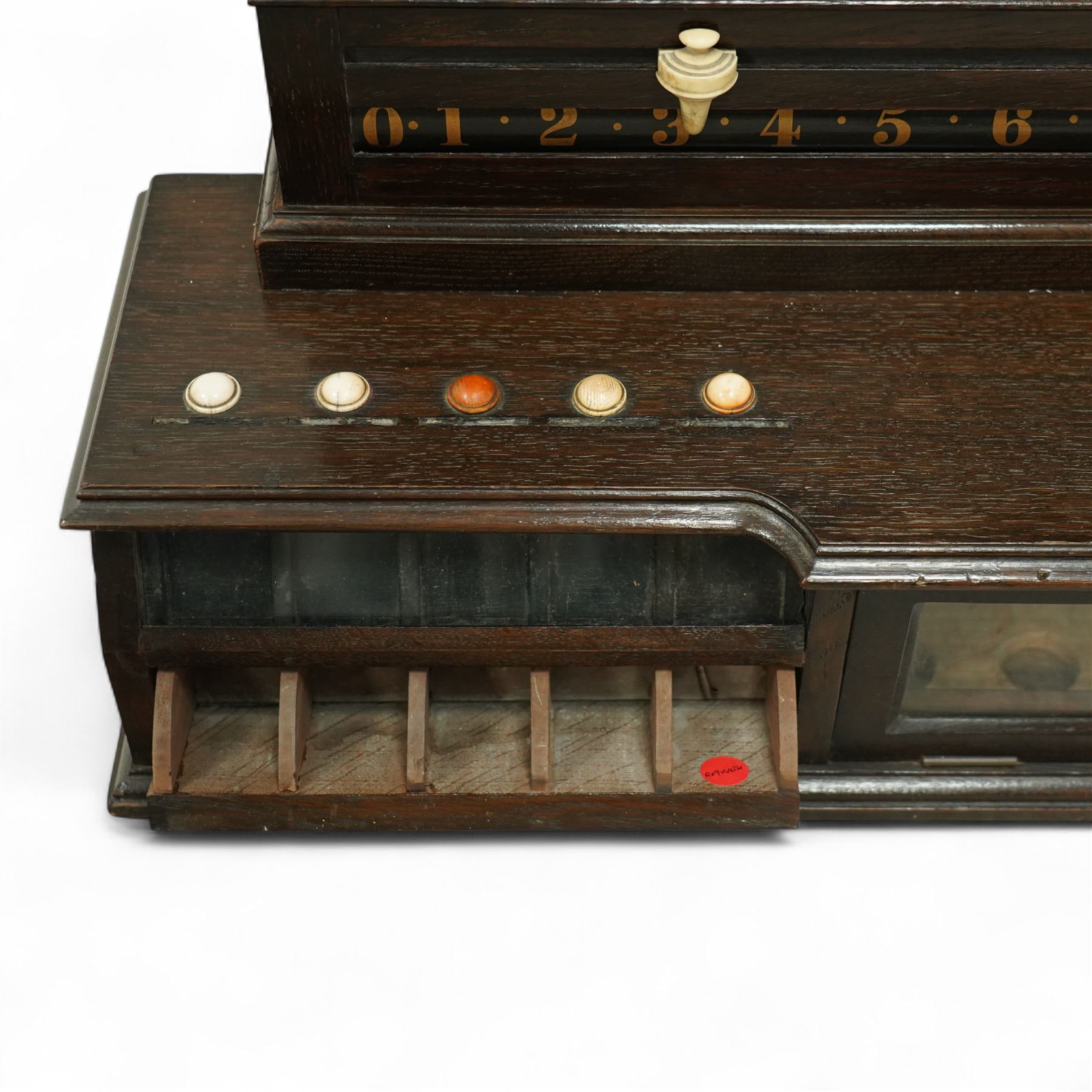 Victorian wall-mounted oak and walnut cased scoreboard,  moulded top, with a name stencilled in the frieze ‘J. Ashcroft, Victoria Street, Liverpool’, the board with chalk panel in the centre for recording scores, sliding panels on both sides for the various games of Billiards and Snooker, two numbered rotating arms with adjustable sliding score keepers, the base section with 5 apertures on each side, and coloured ivory roundels, all with glass front for viewing the tokens inside, with drawers beneath, the centre has a long glass panel for storing billiard balls, circa 1870 This item has been registered for sale under section 10 of the APHA Ivory Act Reference UNEGEBLB
