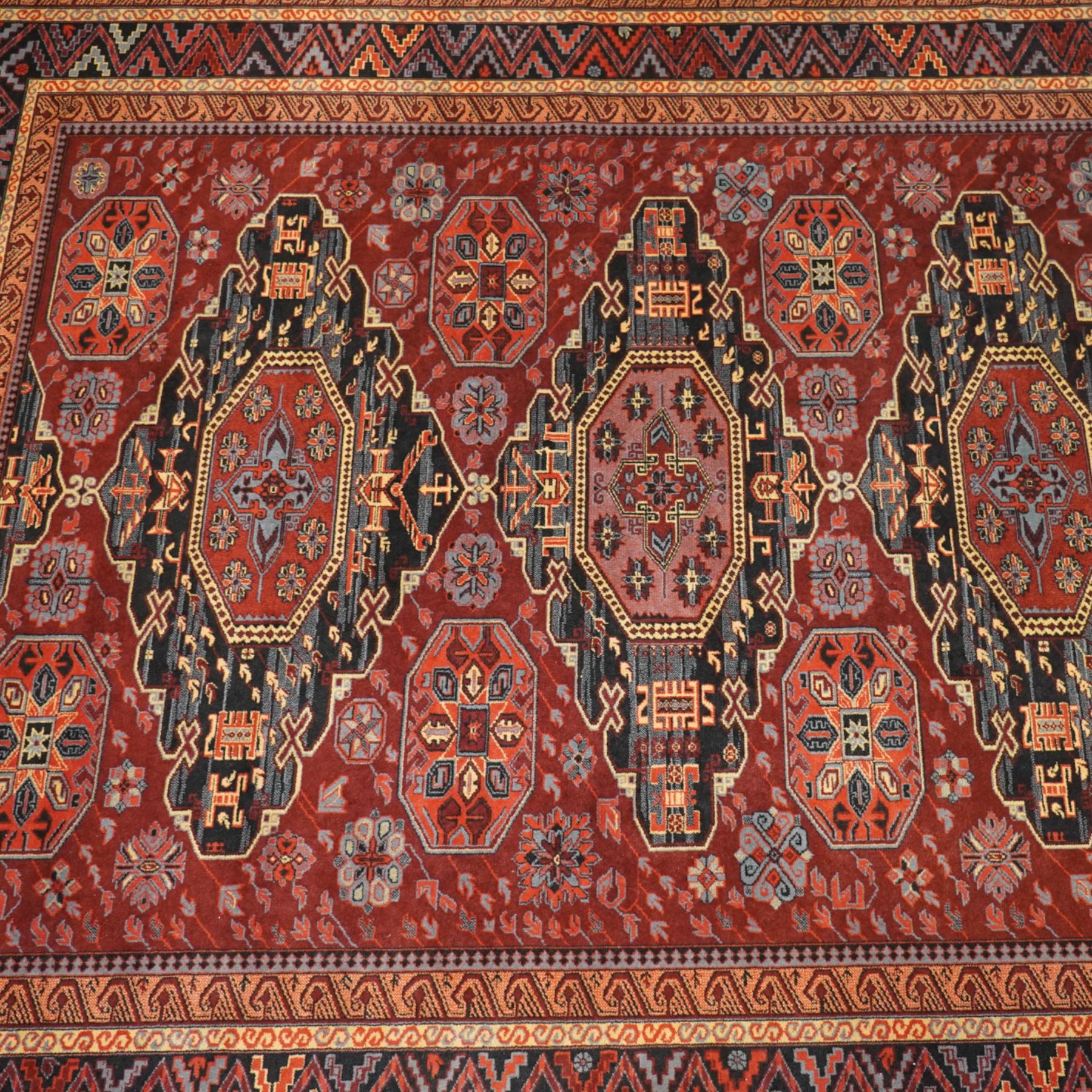 Persian Karabagh design rug, red madder field with three linked octagonal medallions surrounded by floral geometric motifs within multiple stylized borders 