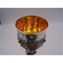 German silver chalice, the bowl, stem and foot each with 19th century repousse and chased decoration depicting putti masks, C scrolls and flowers, set with two hand painted porcelain roundels, possibly Berlin, and six later applied enamel roundels, each depicting religious scenes, the gilded bowl upon knopped stem and spreading octofoil foot, the base with marks for Munich, c.1695 and maker's mark FK