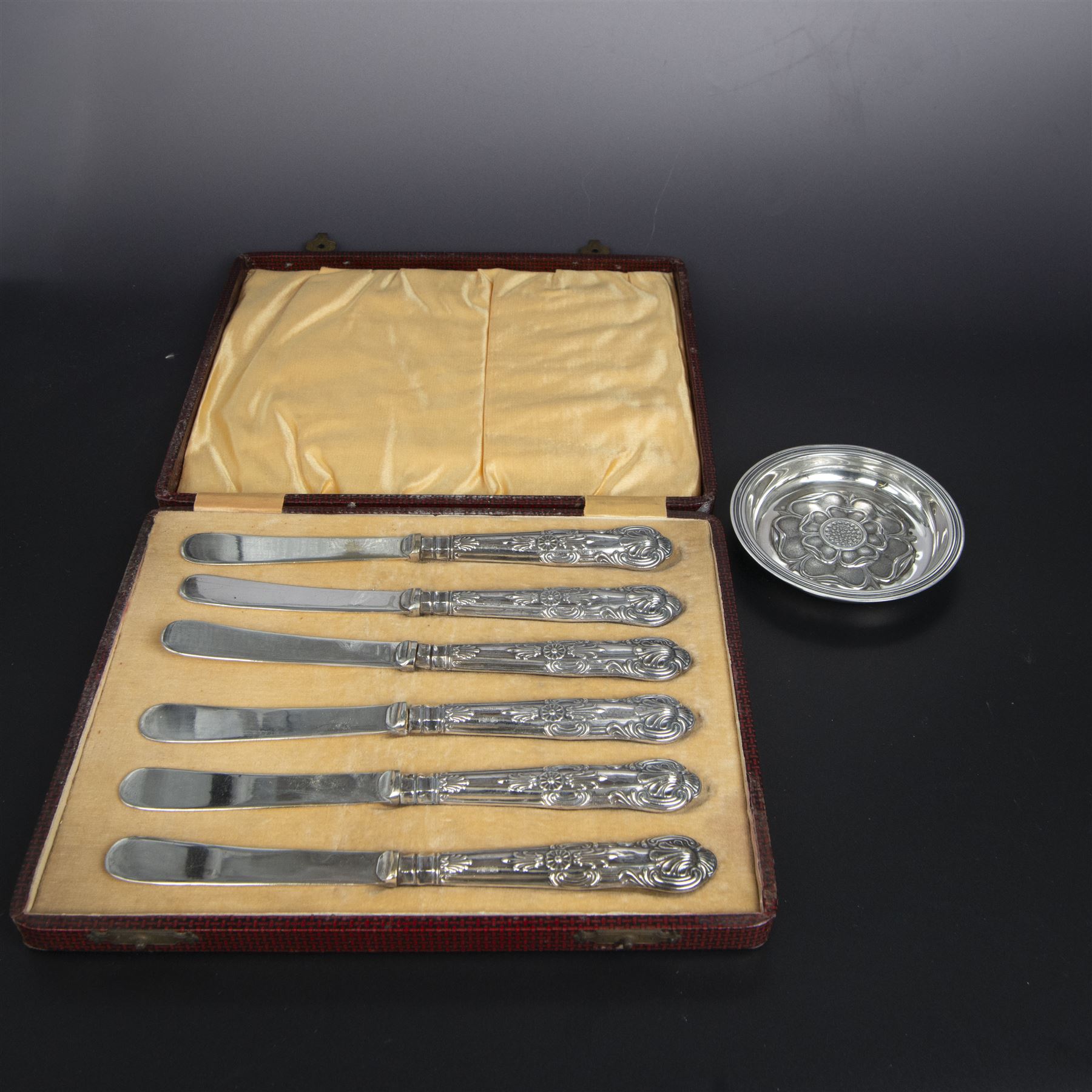 Late 20th century silver pin dish, embossed with Yorkshire rose to centre, hallmarked C J Vander Ltd, London 1971, together with a set of six silver handled King's pattern tea knives, hallmarked Kirby Beard Ltd, Sheffield 1928, contained within fitted case
