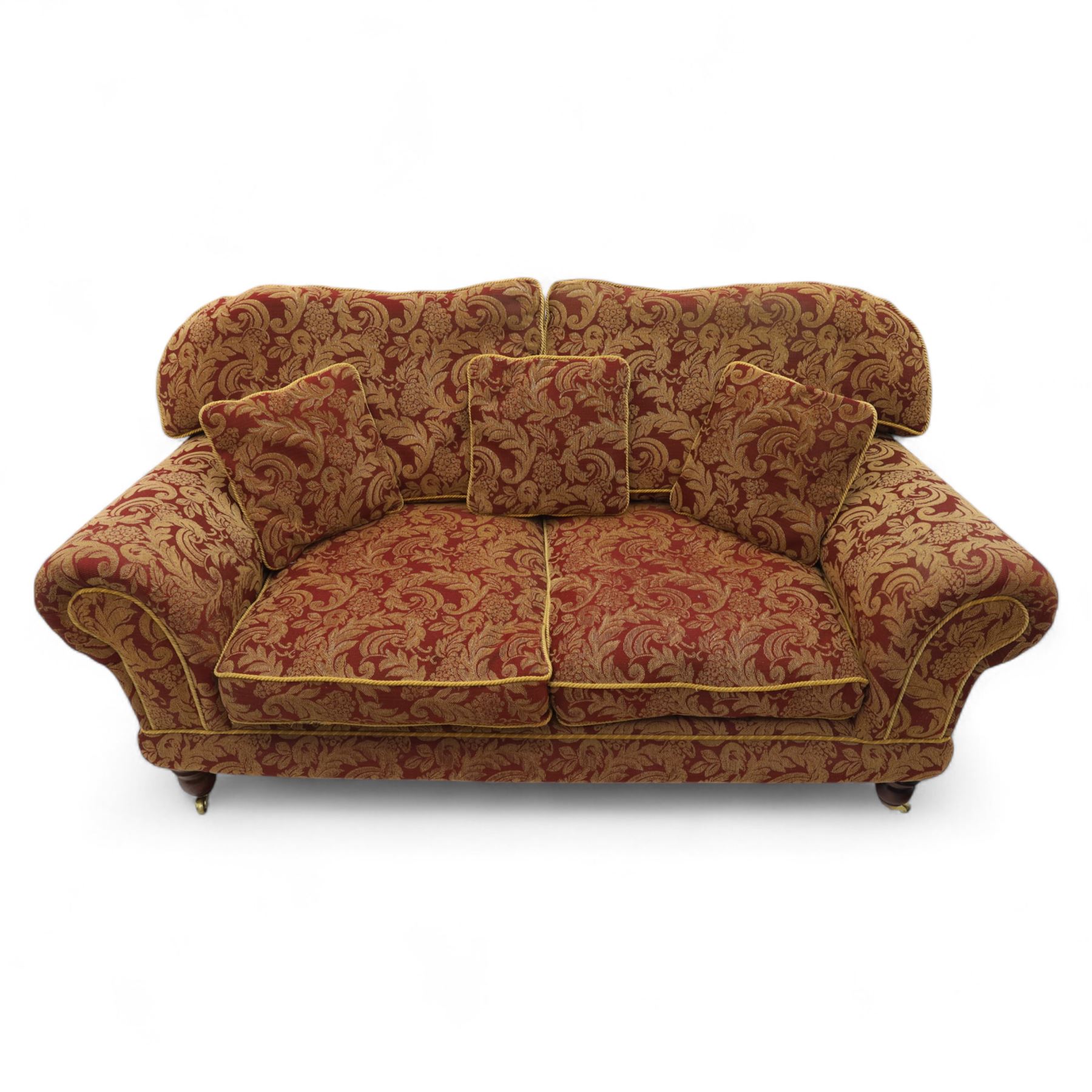 Duresta - two seat settee, upholstered in red and gold damask fabric with piped edges, scroll arms and loose feather-filled cushions, raised on turned wooden feet with brass castors