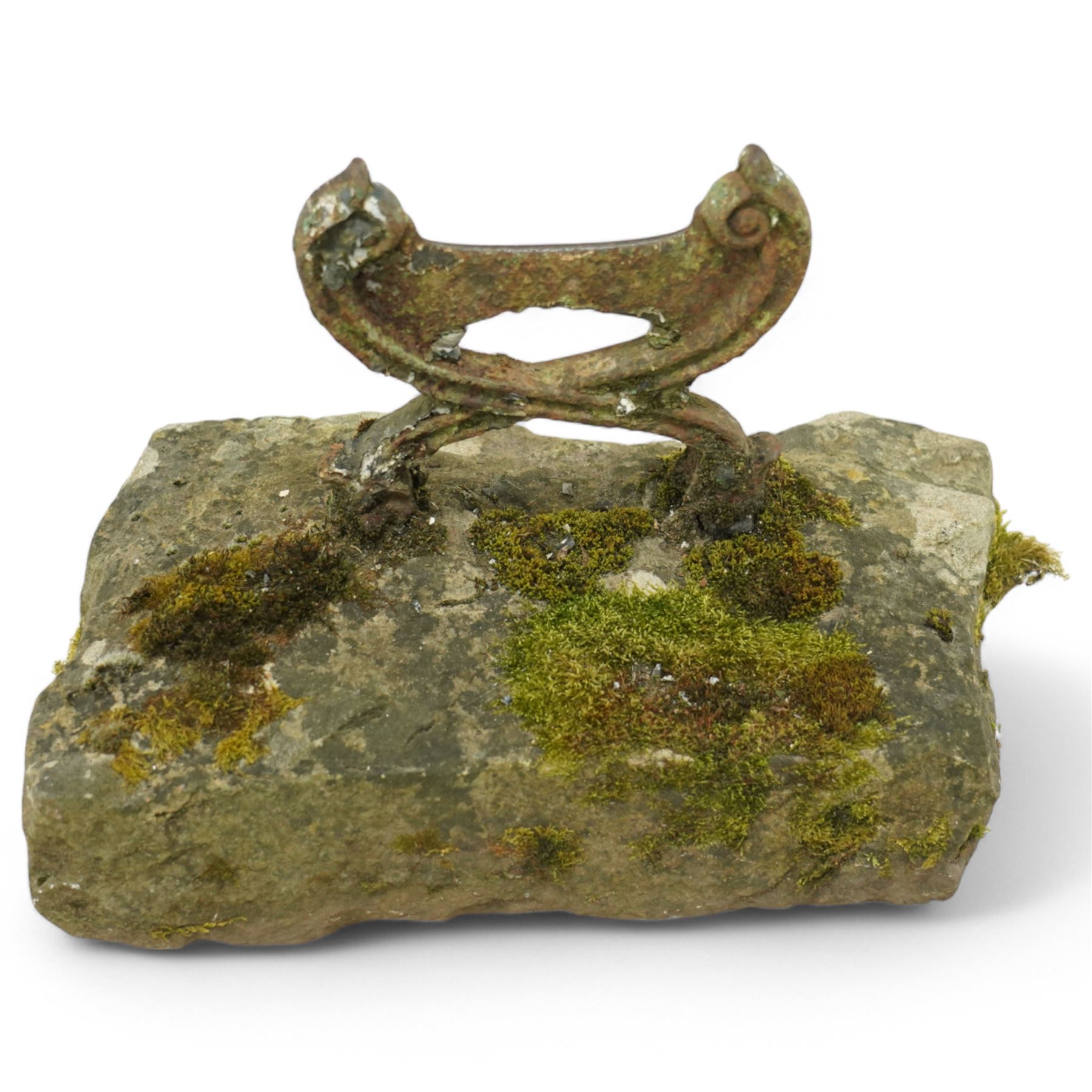19th century cast iron boot scraper, with scrolled upright mounts, set into a rectangular moss-covered stone base