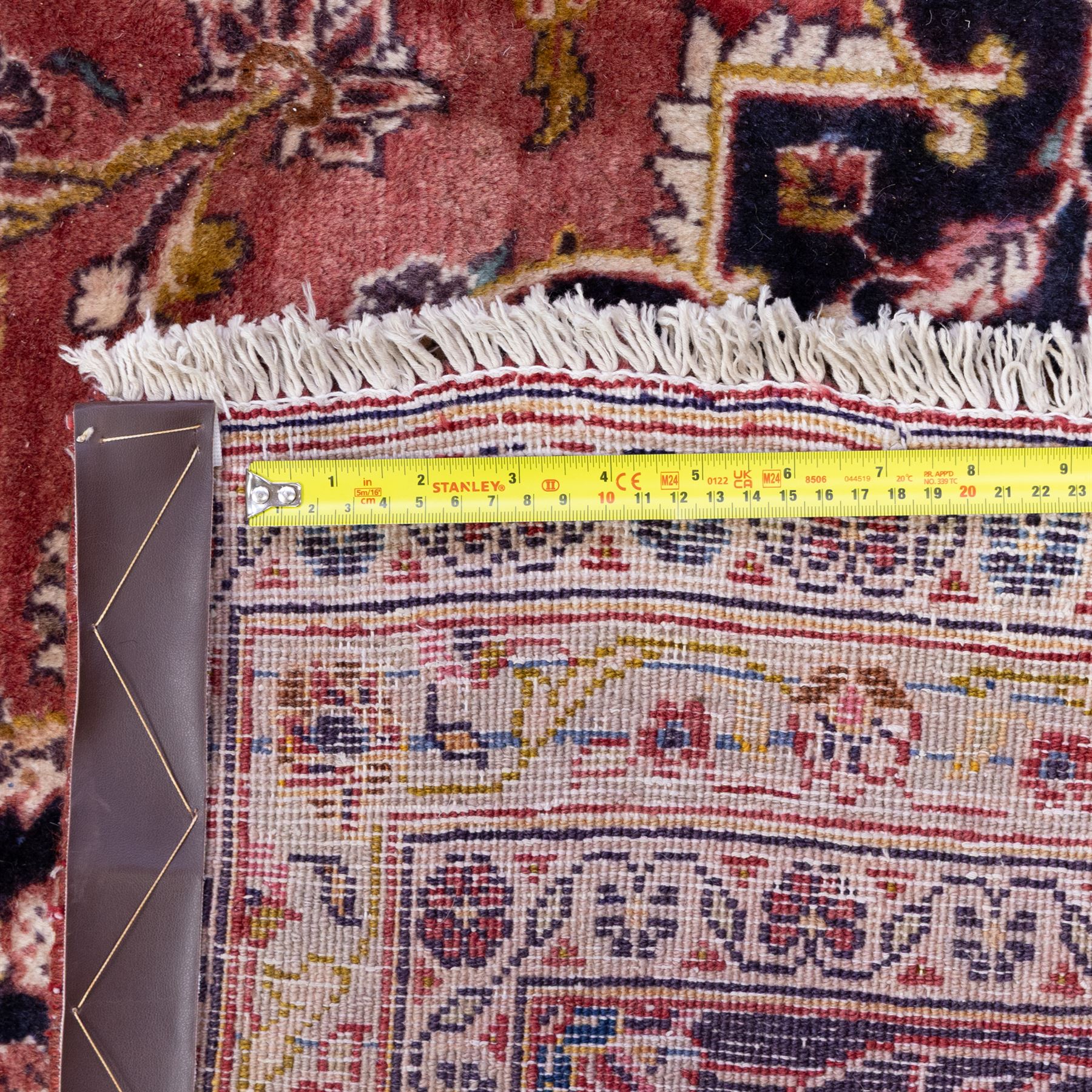 Large Central Persian Kashan hand-knotted carpet, madder red field with central cusped medallion on beige ground enclosed by indigo border with an intricate all-over arrangement of scrolling vines and floral motifs within conforming spandrels and a indigo ground main border ornamented with floral designs, enclosed by guard stripes and cotton fringe ends 