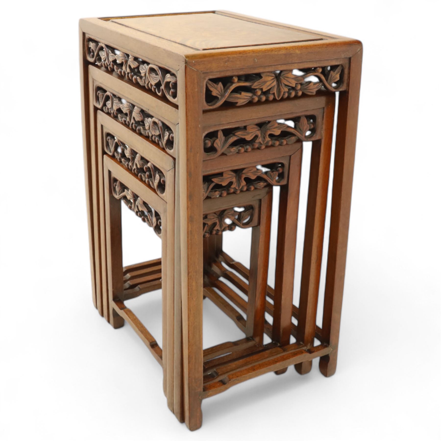 Early 20th century Chinese style hardwood quartetto nest of tables, each with panelled top and carved and pierced vine motif frieze, on square legs united by straight stretchers