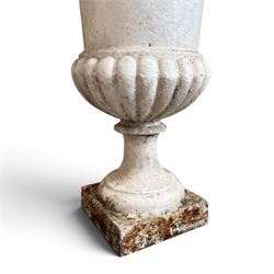 Pair of Victorian revival cast iron garden urns, egg and dart rim, tapering column with gadrooned waist, on square base, finished in distressed white paint