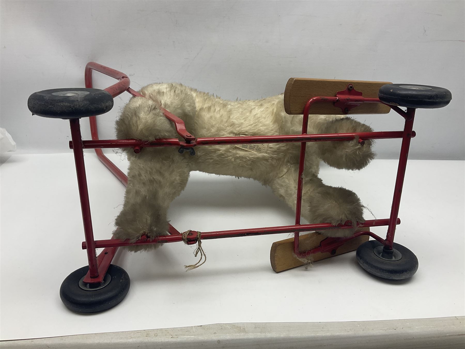 Tri ang - Pedigree Soft Toys - push along/ride-on dog as a wood wool filled plush Airedale terrier in red tubular frame with beech footrests and black rubber wheels; stitched Northern Ireland label in tact L60cm H61cm
