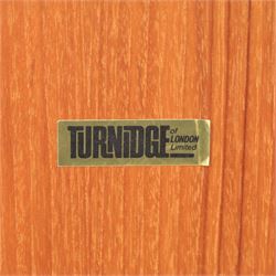 Turnidge of London - Mid 20th century teak drinks cabinet, shaped top with hinged fold-out side sections, twin doors with recessed handles enclosing fitted shelving and serving surfaces, sliding glass doors to the back, on a plinth base above castors