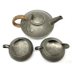 Archibald Knox for Liberty & Co Tudric pewter three piece tea service, comprising teapot with woven reed handle, single handled open sucrier, and milk jug, each with planished finish and detailed with honesty flowers, each impressed beneath Made in England Tudri Pewter 0231 