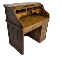 Early 20th century oak roll-top desk, the tambour enclosing pigeon holes and small drawers, the base fitted with slide, a single long drawer and three smaller drawers