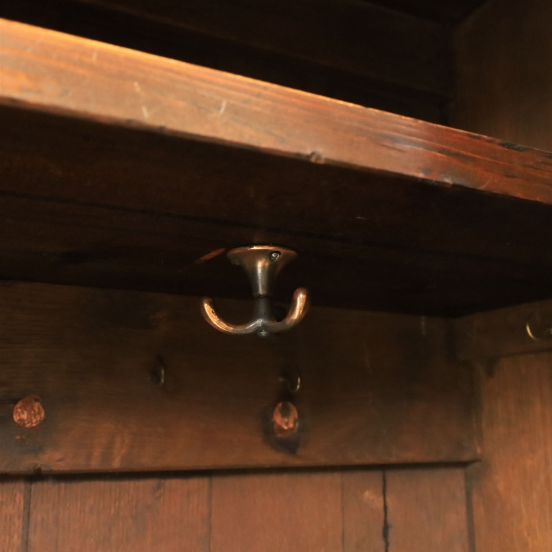 20th century dark stained oak hall robe, cantered sides enclosing a hooks and a shelf, panelled and carved sides, raised on stile supports