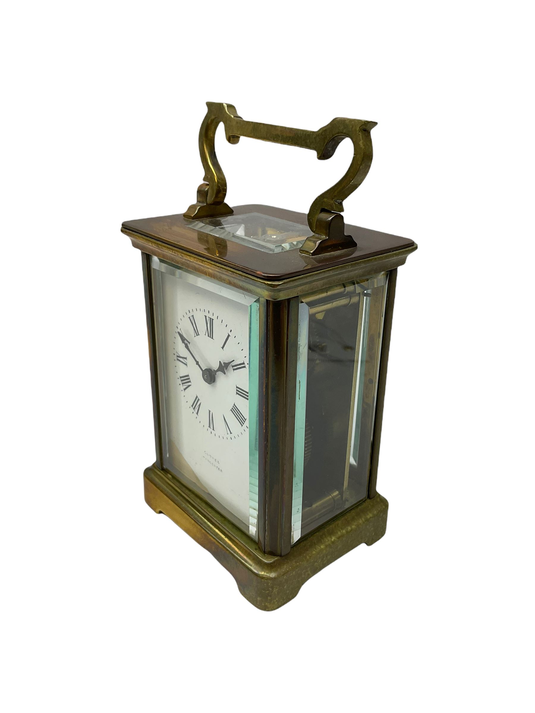 An early 20th century French timepiece carriage clock in a Corniche case with a white enamel dial , Roman numerals, decorative steel hands and minute markers, four bevelled glass panels and a rectangular panel to the top, with a replacement jewelled lever platform escapement with timing screws.