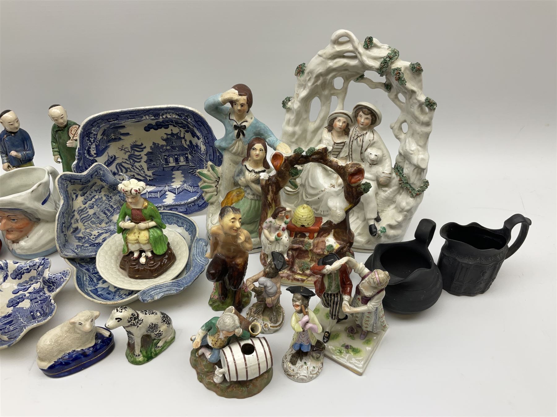 Two 19th century blue and white pickle dishes, each decorated in a variant of the Willow pattern, 19th century blue and white Willow pattern dessert dish, further Willow pattern dish, two black basalt jugs, small Victorian cockle dish, plus a group of Victorian and later figures, to include two Staffordshire arbour groups, one with beehive, Staffordshire style model of a sheep, two Sitzendorf monkey band figures, a Continental figure group modelled as a dancing couple, Atlas China figure of a Satyr, two jugs modelled as Punch and Judy, Rd no 139844, etc. 