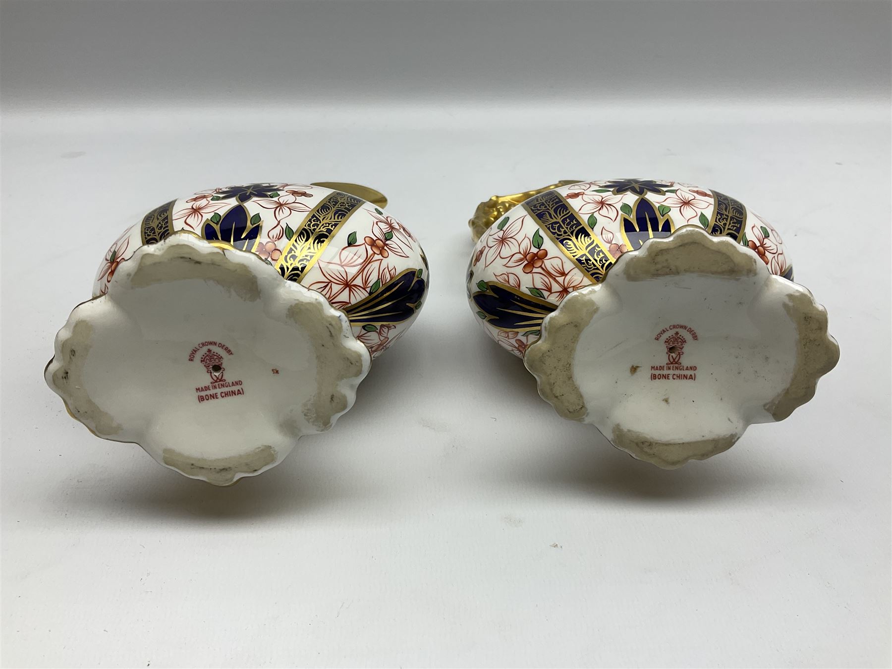Pair of mid 20th century Royal Crown Derby Imari 1128 pattern Kedleston ewers, each with gilt scroll handle and neck, upon a gilt quatrefoil foot, each with printed marks beneath, H25.5cm
