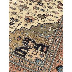Persian Heriz pale olive and ivory ground carpet, large quatrefoil medallion with palmettes, the surrounding field decorated with trailing leafy branches and stylised plant motifs, peach ground borders with overall floral pattern, within guard stripes 