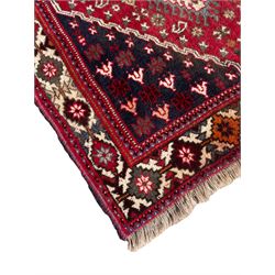 Persian Shiraz rug, red ground and decorated with three bands of stepped lozenge medallions, decorated with small geometric and stylised motifs, the border with repeating geometric design