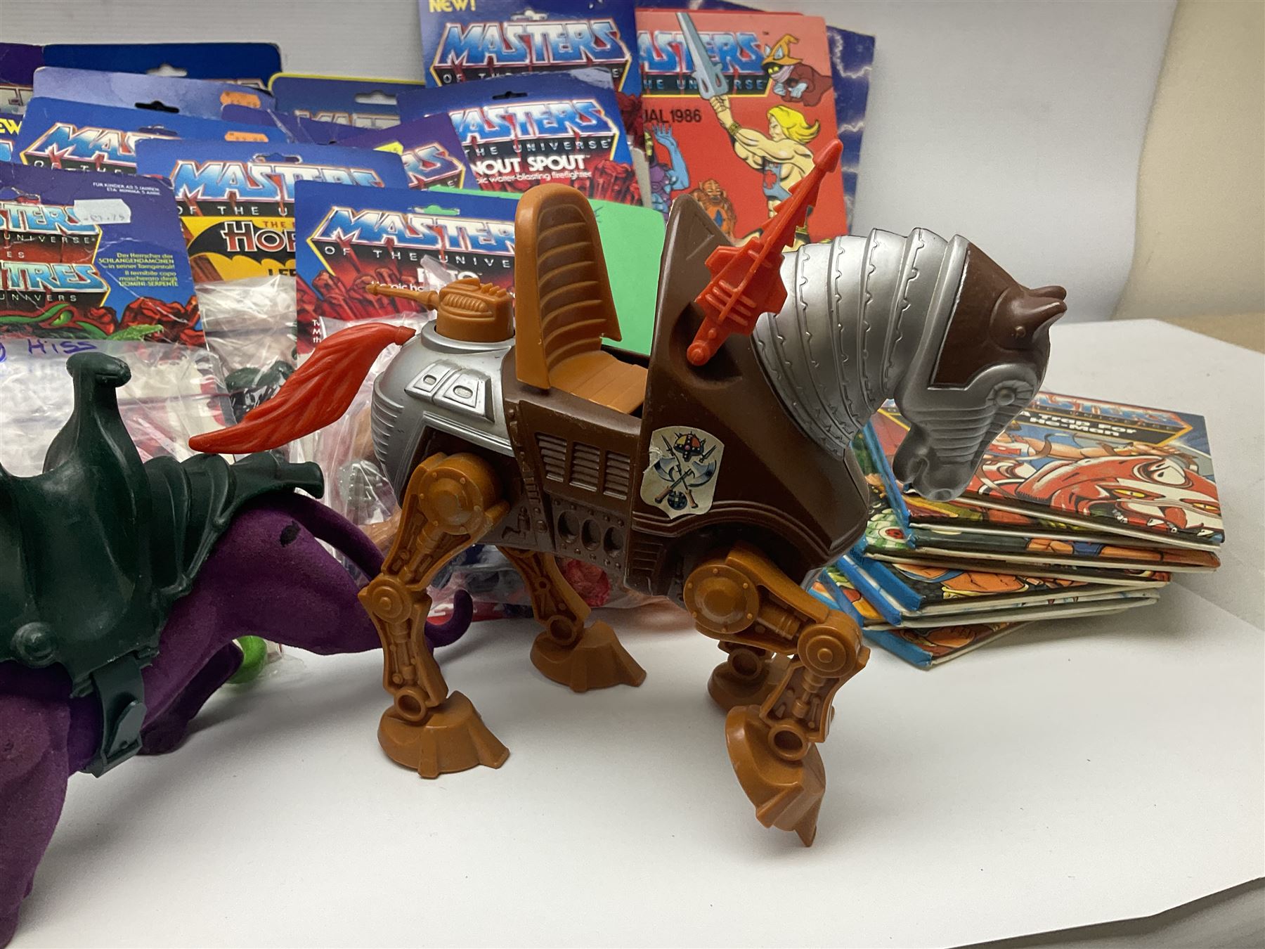 Thirty-one Masters of the Universe He-Man figures re-bagged on original backing cards;  two others lacking backing cards; boxed Modulok figure; bag of weapons and accessories; Roton, two horses and two battle cats; 1986 & 1987 Annuals; Ladybird and other story books; Panini sticker album; instructions etc