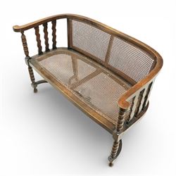 20th century bergère two seater settee, with shaped curved top rail and downswept arms, the back and seat fitted with woven cane panels, supported by turned uprights and legs united by a carolean stretcher 