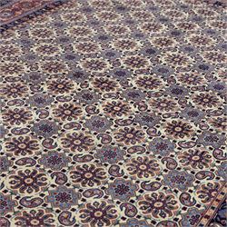 North West Persian Tabriz hand-knotted carpet, ivory field densely decorated with an all-over Herati style (Mahi) lattice composed of stylized rosettes and scrolling leaves, enclosed by a broad madder-red border of palmette and floral vine design, between navy guard stripes, cotton fringe ends 