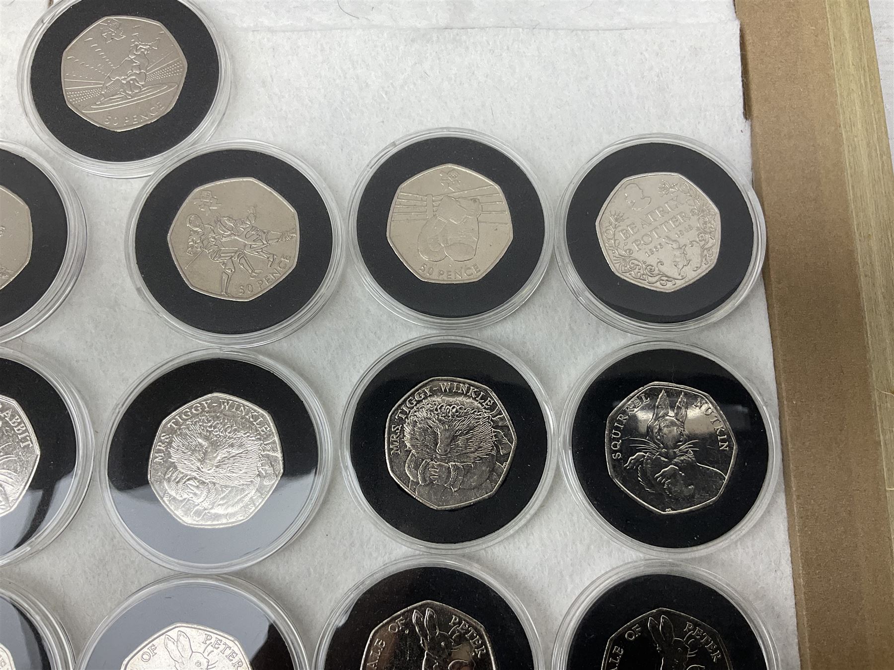 Thirty-seven commemorative fifty pence coins, including 2011 wrestling, other Olympics, Beatrix Potter etc, housed in capsules