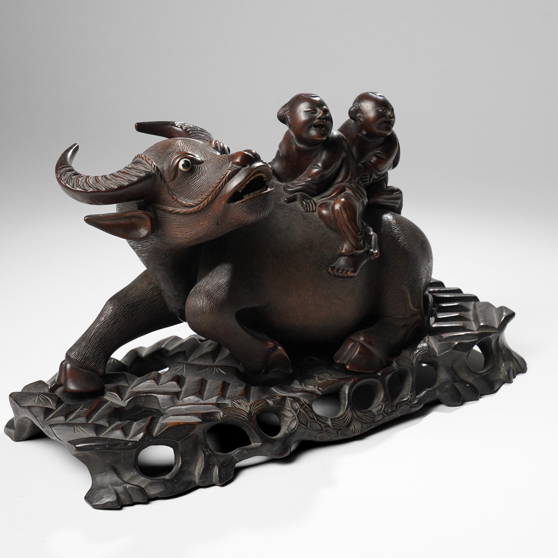 Early 20th century Chinese carved hardwood figural group of two boys on the back of a water buffalo on wooden stand W37cm