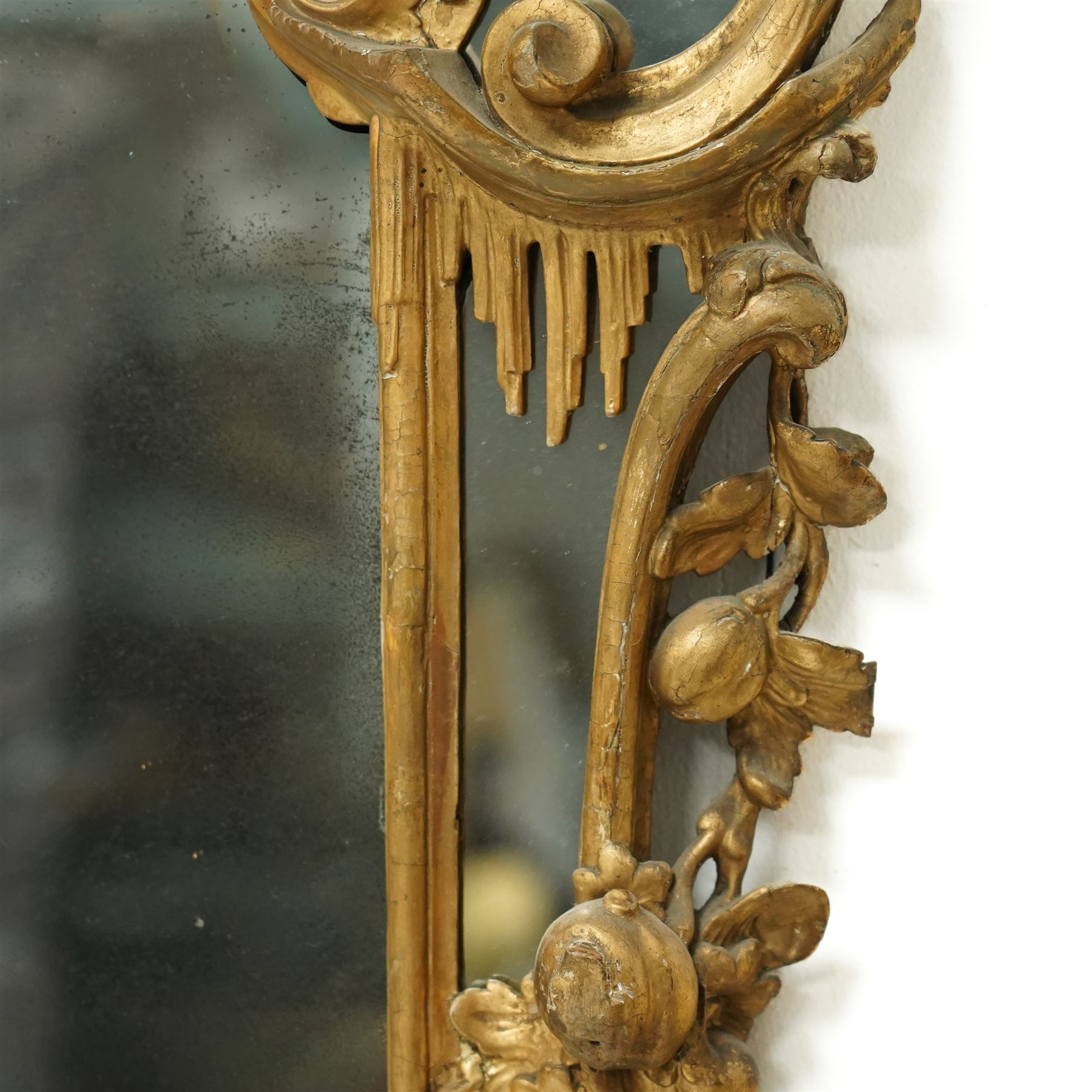 George III Chippendale design carved giltwood and gesso wall mirror, the impressive protruding pierced pediment decorated with flared acanthus leaves interspersed with flower heads and berries, over an arched outer-frame - the cresting comprised of C-scrolls carved with dripping icicle motifs, the uprights formed of scrolling acanthus with swags of grapevines and foliage, over a scrolled cartouche terminal, the inner-frame of architectural form with bell-flower details and a shaped cresting with scrolling acanthus leaves, all enclosing a central slightly bevelled rectangular mercury glass plate, surrounded by smaller plates