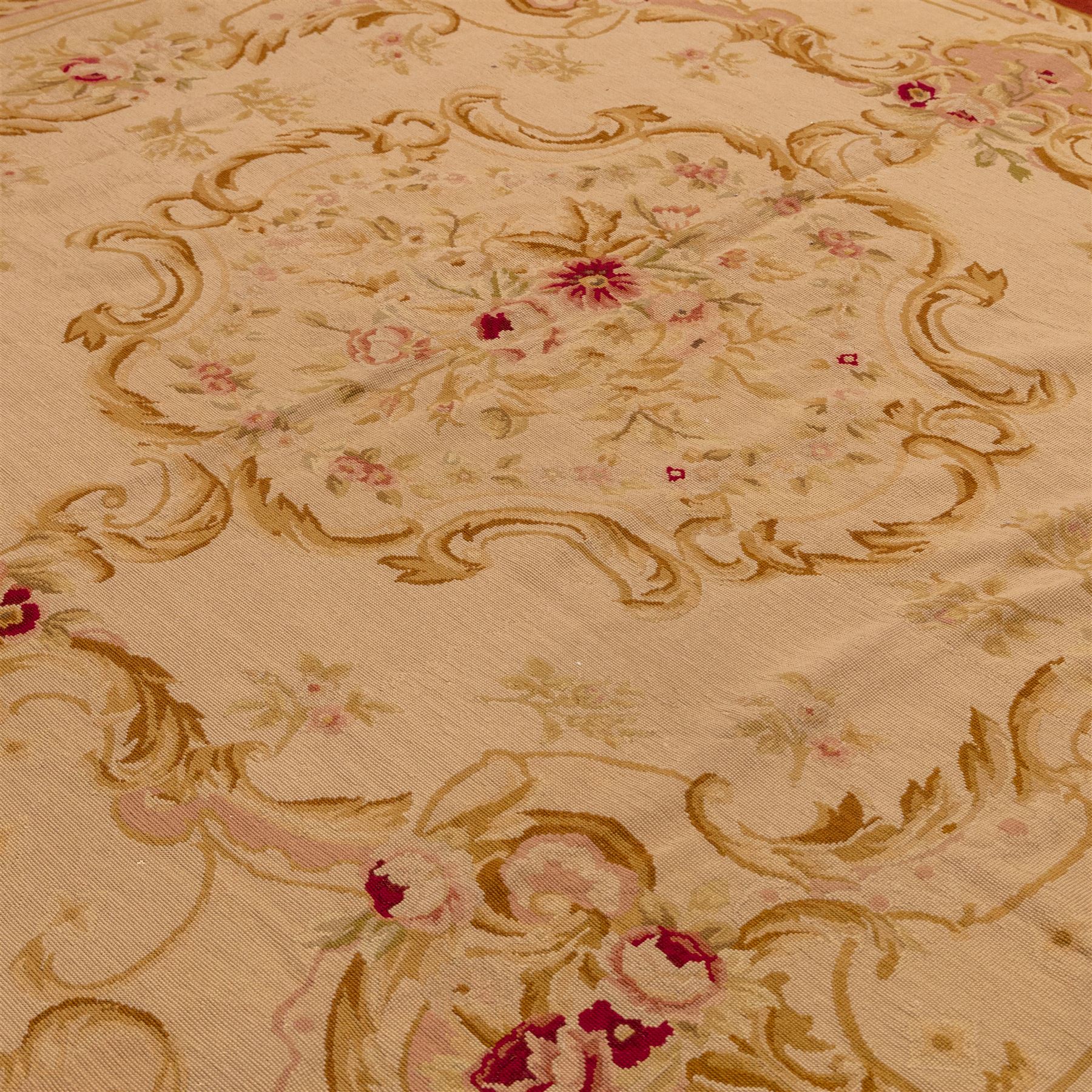 20th-century Aubusson-style tapestry wall hanging of square form, woven with a central floral medallion composed of delicate sprays in soft pinks, creams, and muted greens, framed by scrolling acanthus ornamentation and floral cartouches to each corner, all set within a pale ivory ground and enclosed by a terracotta toned border 