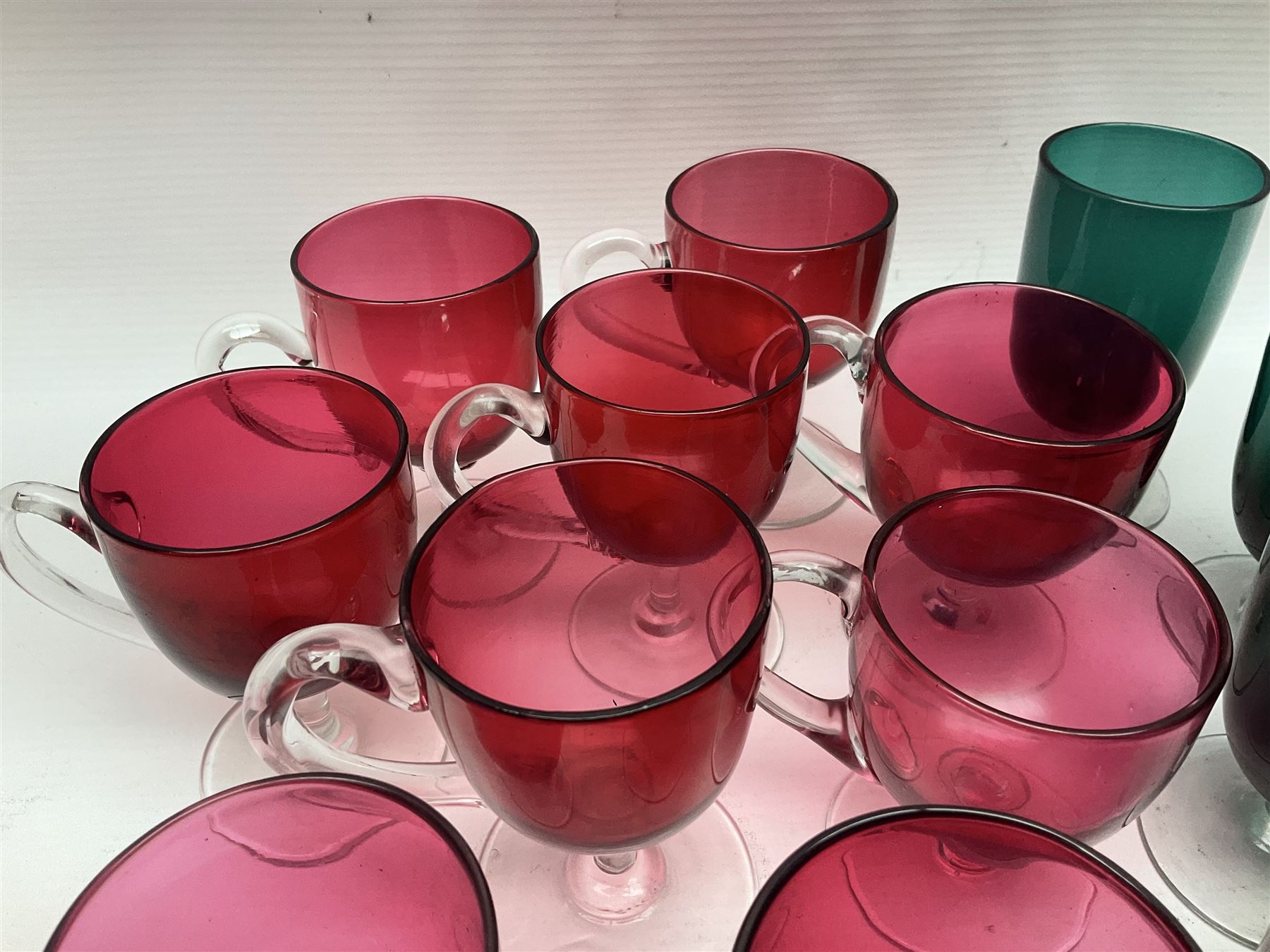 Collection of 19th century coloured glasses, to include nine cranberry glass punch cups, each with clear glass handle and foot and a set of six green glasses, with short clear stems, tallest H10cm