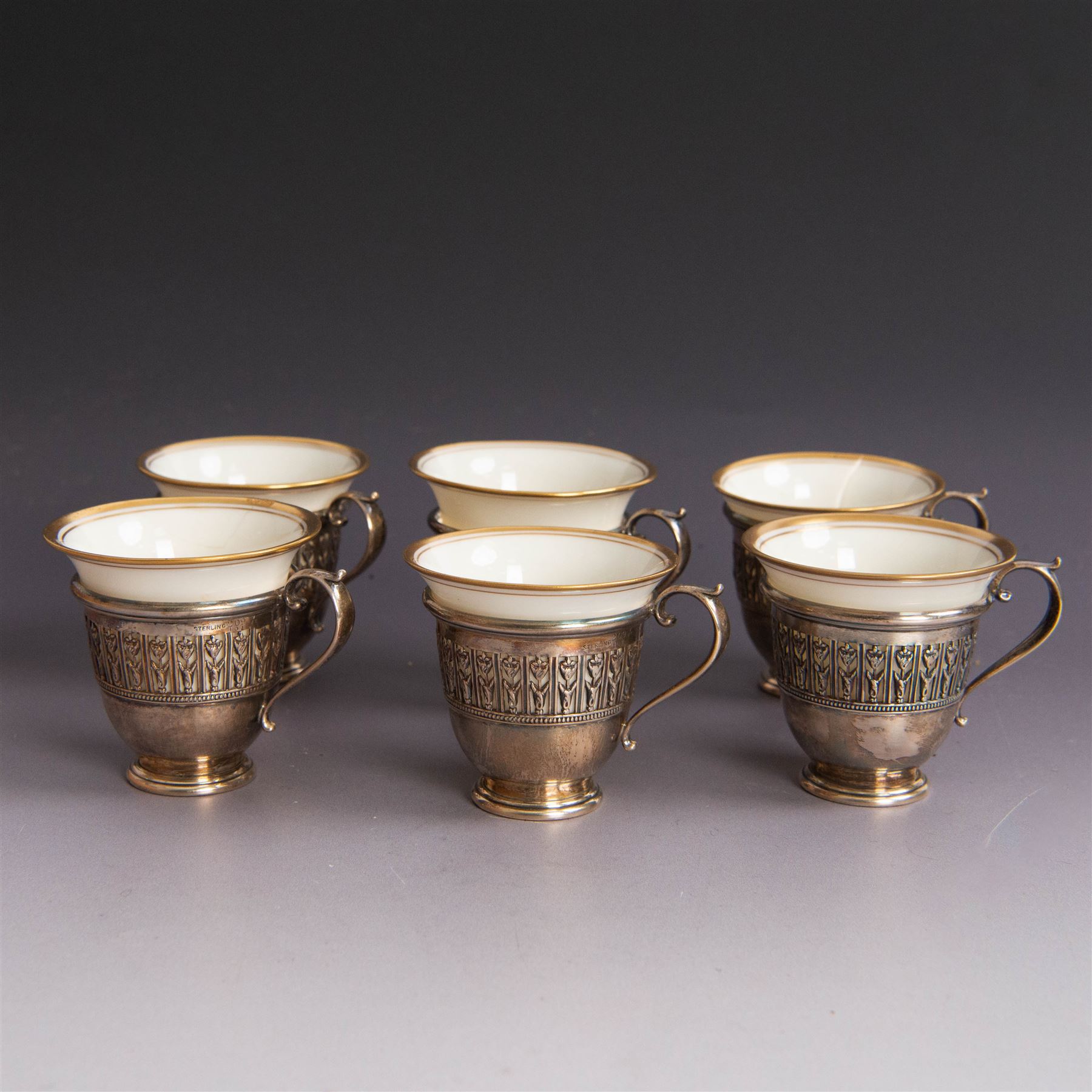 Set of six Lenox porcelain coffee cups, with gilt rims, each with American silver openwork cup holders, stamped sterling