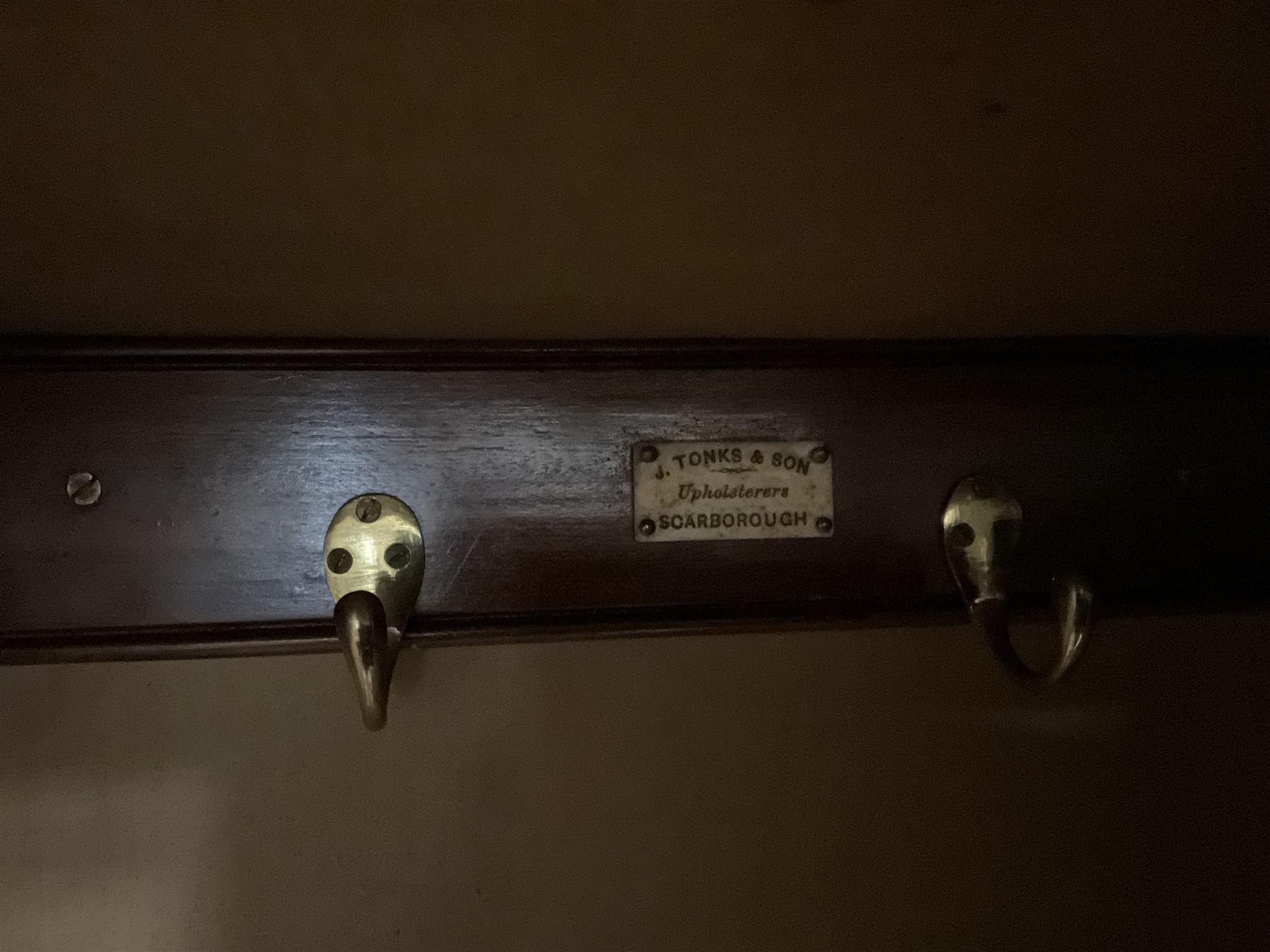 Edwardian walnut combination breakfront triple wardrobe, projecting cornice over cushioned and fluted frieze, central fielded panelled cupboard carved with foliate decoration above two short and three long drawers, flanked by two bevelled mirror doors enclosing hanging hooks with single drawers to base, retailed by J Tonks & Sons, Scarborough