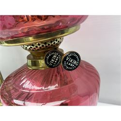 Victorian cast brass oil lamp, with fluted pink glass shade, together with two smaller brass oil lamps with pink shades and reservoirs and a pair of oil lamps, the bases modelled as putti, with pink glass reservoir  and frosted shades, tallest H70cm