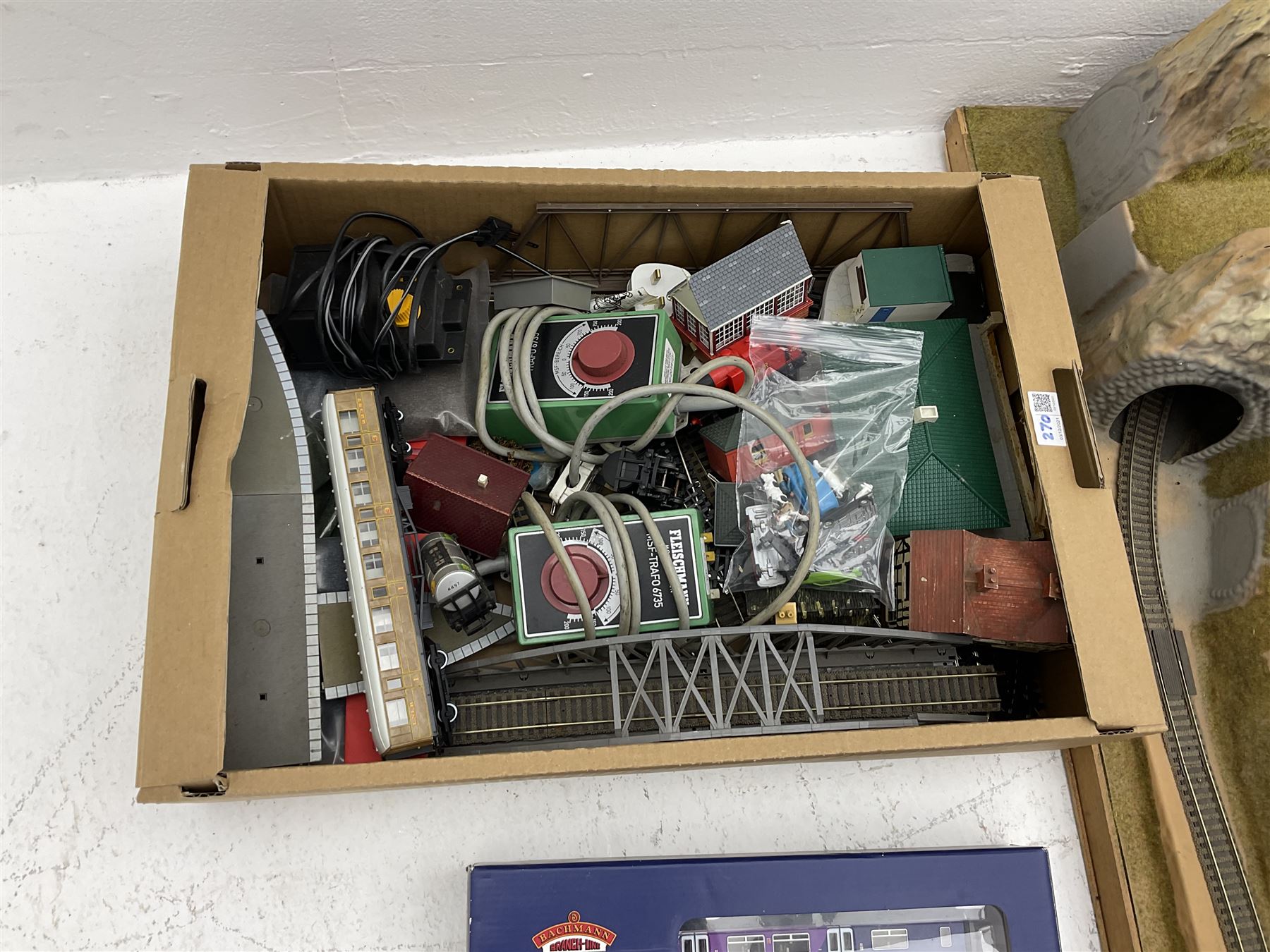 '00' gauge - table-top moulded plastic model railway layout with various rocky outcrops, tunnels, waterfall to lake, loops of Fleischmann track supplemented by Hornby track, bridges, kit built buildings and other accessories; together with Bachmann Class 150 2-car DMU Set and Hornby Northern Rail Class 142 2-car Set; both boxed; and small quantity of other rolling stock, three controllers etc  200 x 120cm