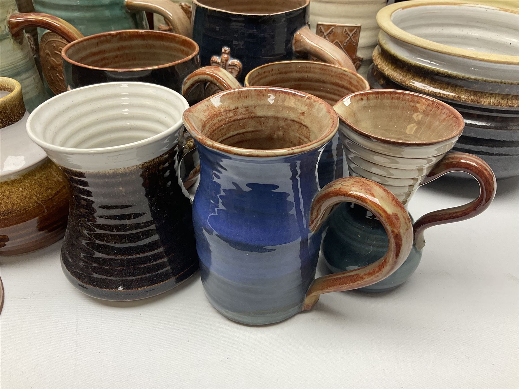 Wold studio pottery tankards, in various colours and relief decoration together with other studio items including vases, jugs and pots 