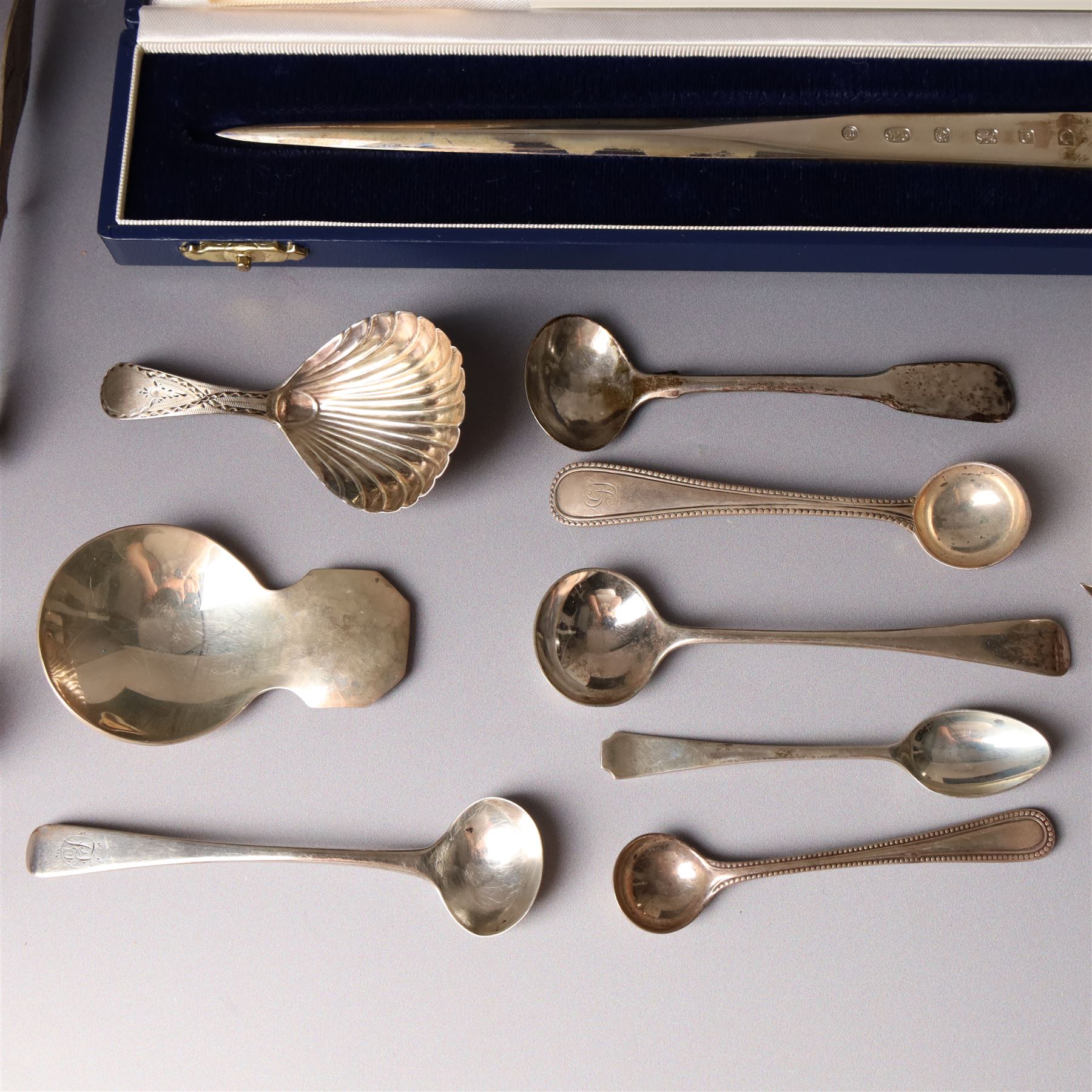 Early 19th century silver caddy spoon, Elizabeth II caddy spoon, various silver condiment spoons, sugar tongs, napkin ring, other silver cutlery and a silver paper knife, boxed