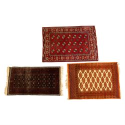 Three rugs,  comprising a Baluch rug in crimson ground, 179x97cm, a Tekke Bokhara rug in c...