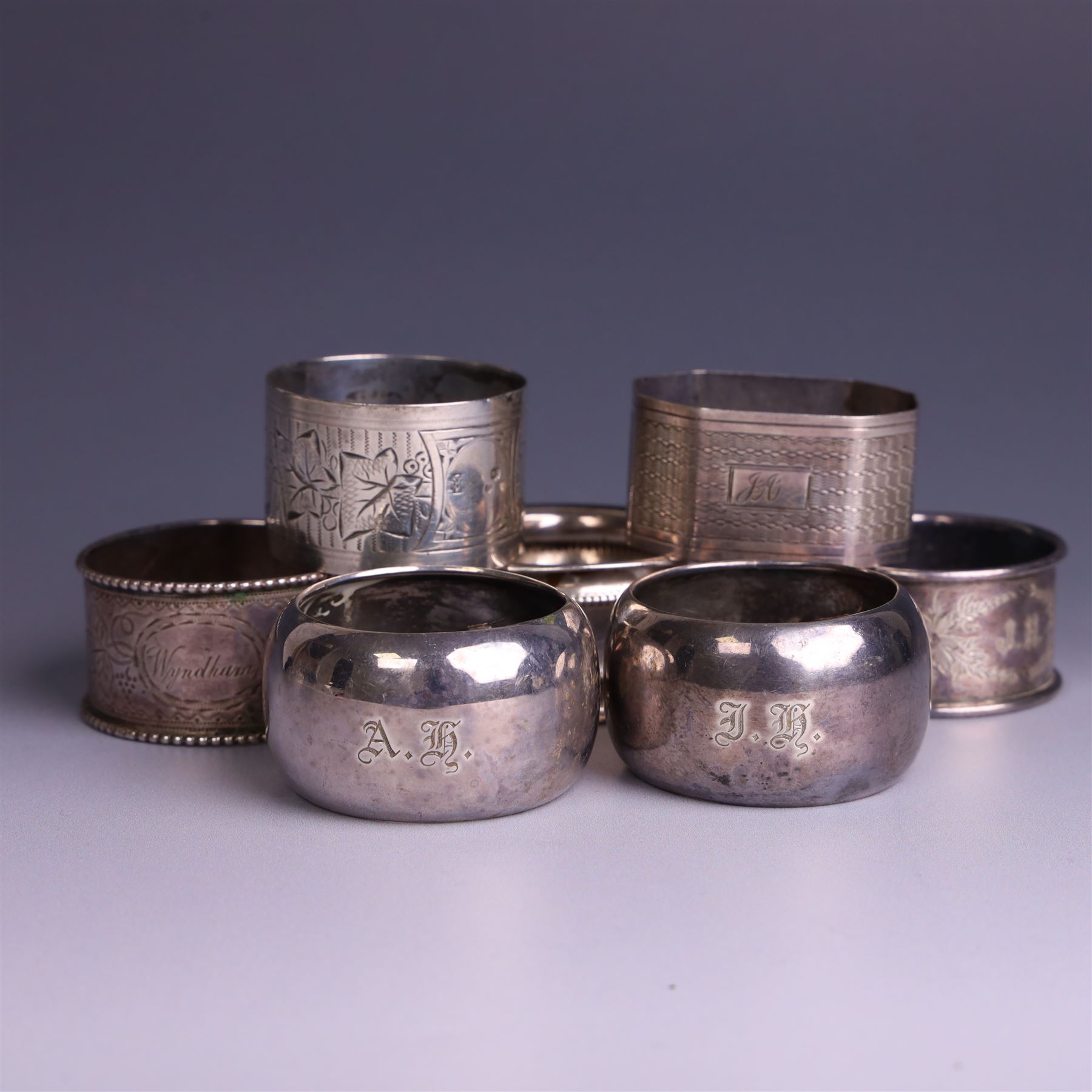 Seven silver napkin rings, of varying design and each with engraved initials, all hallmarked