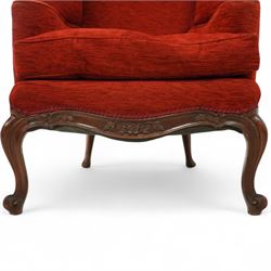 19th century Rococo revival upholstered armchair, red textured fabric over a carved walnut frame, shaped back and sides, floral carved serpentine seat rail, on cabriole supports 