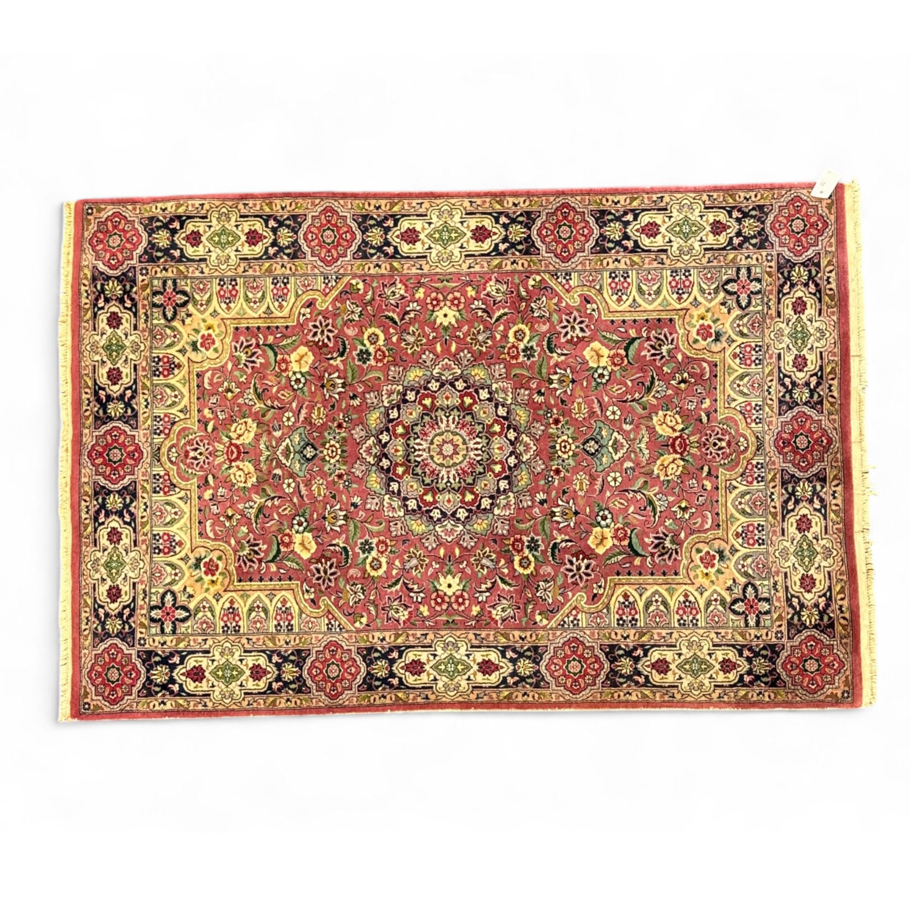 Kashan design hand knotted wool carpet, decorated with an ivory and green floral medallion on a pink ground with scrolling vines, ivory spandrels, multiple navy and ivory borders with stylised flowerheads, from the region of Punjab, Pakistan