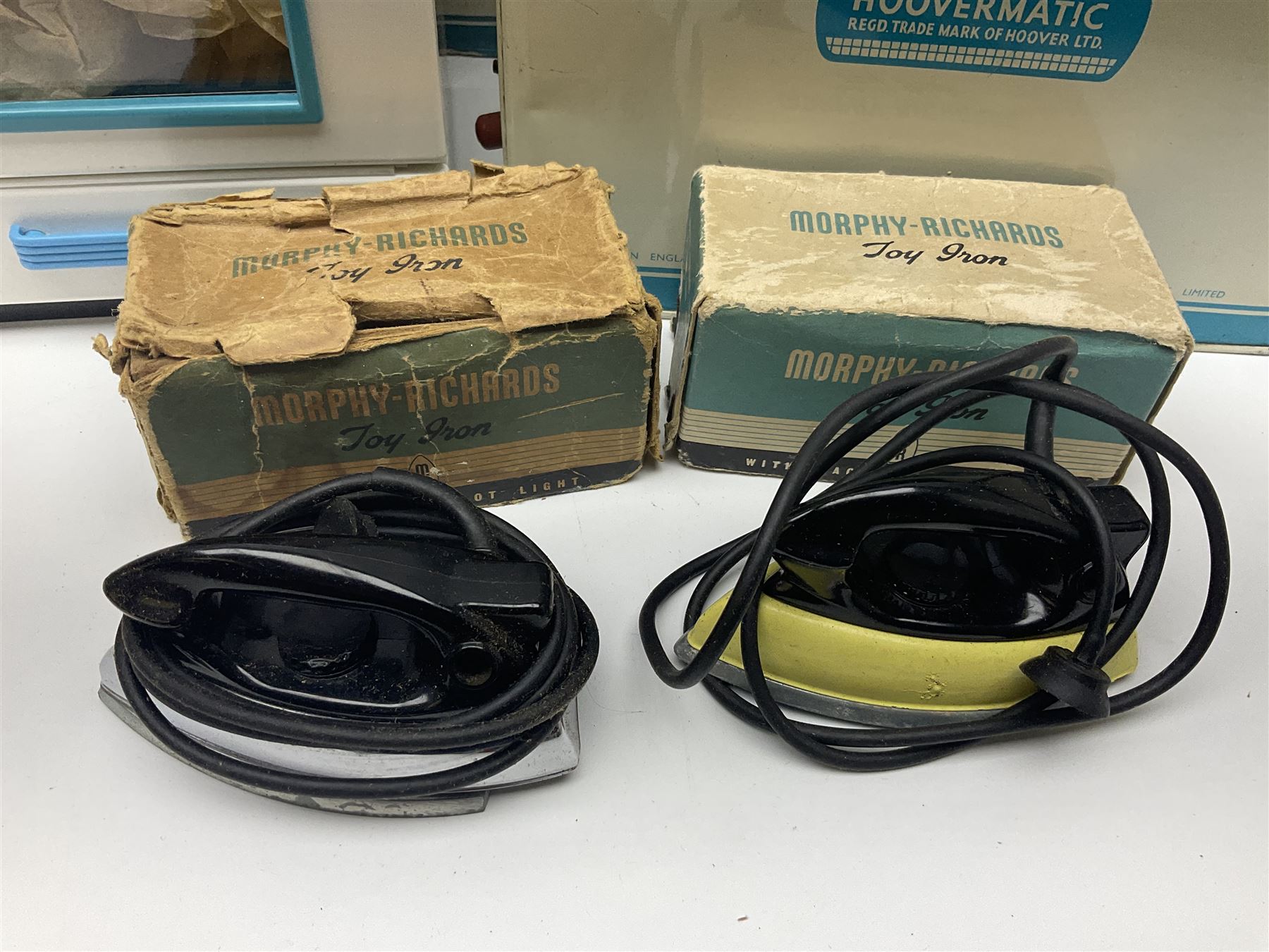 Six toy kitchen appliances - Casdon battery operated cooker; Mettoy Hoover washer; Chad Valley Hoovermatic washer; Wells Brimtoy tin-plate clockwork washer; and two Morphy Richards irons; together with a continental child's Regina sewing machine; all boxed (7)