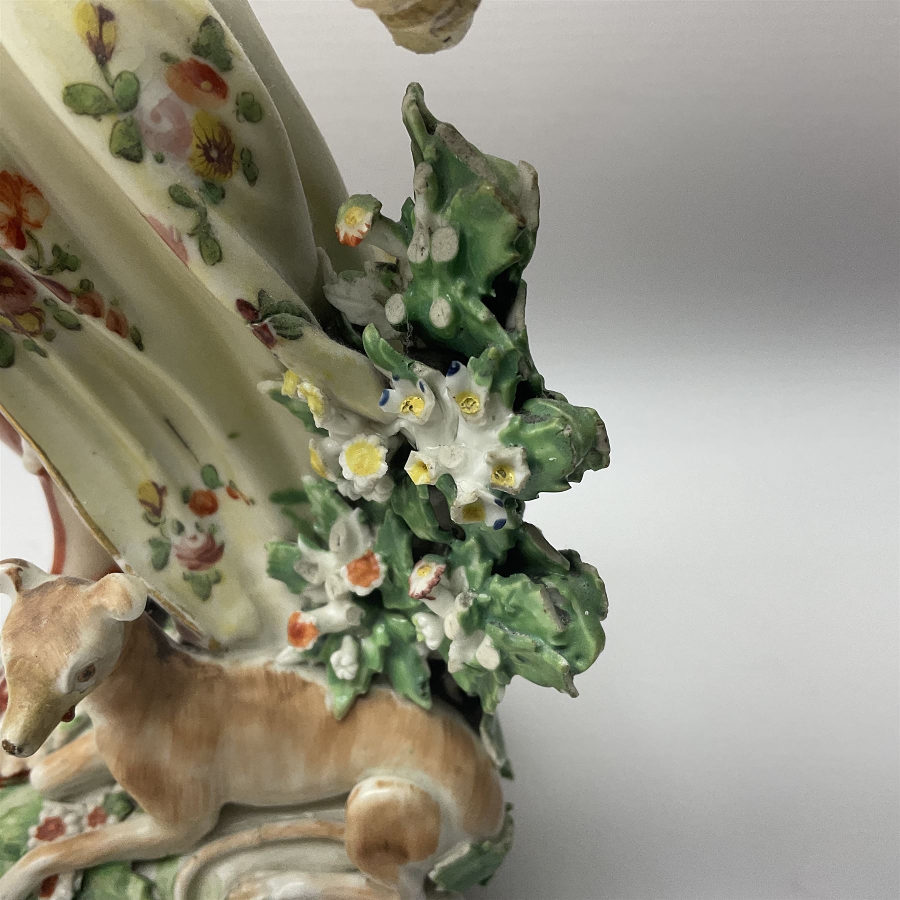 18th century Derby figure of Diana the huntress, circa 1760, modelled reaching for an arrow from quiver across her back, with recumbent hound at her feet, upon a scrolled base with bocage detail, H27.5cm